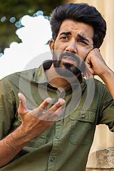 Sad unhappy frustrated indian man standing alone in city street, feeling bad annoyed, grief, problem