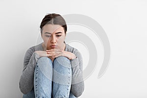 Sad unhappy indifferent caucasian young female suffering from depression sits on floor at home