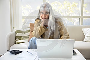 Sad unhappy retired elderly woman looking at accounting work result