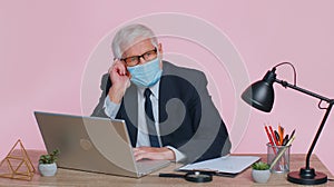 Sad unhappy senior office businessman putting on face medical mask to prevent respiratory infection