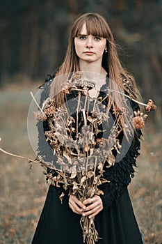 Triste infelice serio bella ragazza lungo capelli possesso da essiccato autunno fiori. una foto buio colori da carino 