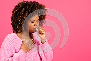 Sad unhappy young black curly female in casual coughing, suffering from sore throat