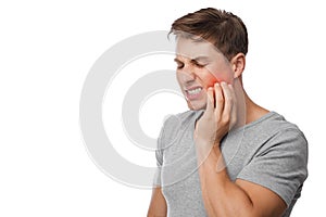 Sad unhappy young handsome caucasian guy suffering from toothache, presses hand to cheek, highlighted in red