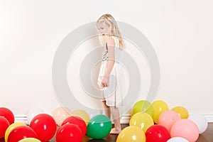 Sad upset little girl celebrating birthday at home alone. Lovely lonely unhappy girl child with colorful balloons. Quarantine