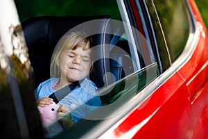 Sad upset little kid girl sitting in car in traffic jam during going for summer vacation with his parents. Tired