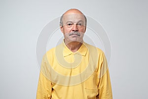 Sad upset mature hispanic guy in yellow pullover looking with guilt and sadness