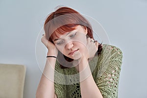 Sad upset teenage female, red-haired girl 19, 20 years old face close-up