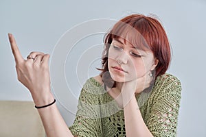 Sad upset teenage female, red-haired girl 19, 20 years old face close-up