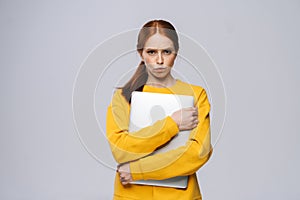 Sad upset young business woman or student holding laptop computer and looking at camera