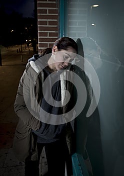 Sad woman alone leaning on street window at night suffering depression crying in pain