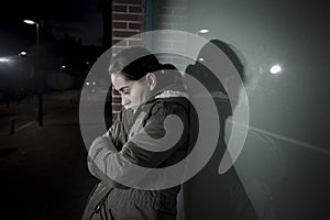 Sad woman alone leaning on street window at night suffering depression crying in pain