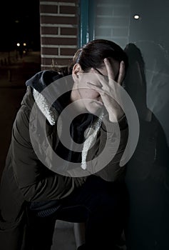 Sad woman alone leaning on street window at night suffering depression crying in pain