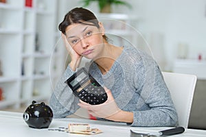 Sad woman with calculator and bills on table