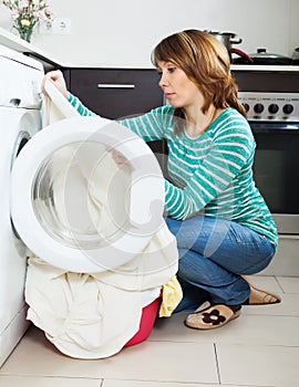 Sad woman cheking clothes near washing machine