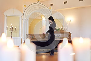 Sad woman with coffin at funeral in church