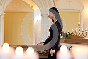 Sad woman with coffin at funeral in church