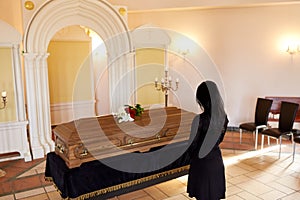 Sad woman with coffin at funeral in church