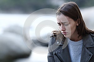 Sad woman complaining looking down on the beach