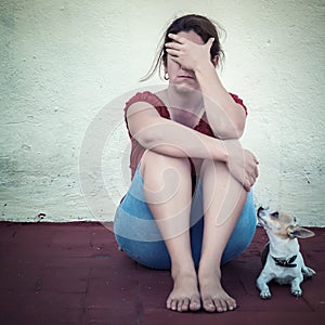 Sad woman crying with a small dog besides her