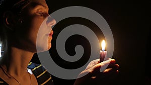 Sad woman deep in prayer with a candle in hands. Seeking help, despair in her eyes. 4K UHD.