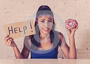 Sad woman on diet holding a sign help resisting temptation to eat chocolate and donuts