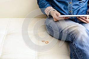 Sad woman after the divorce, looking at a family photo in the frame sitting on the floor near the sofa in the room. Concept of div