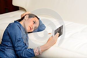 Sad woman after the divorce, looking at a family photo in the frame sitting on the floor near the sofa in the room. Concept of div