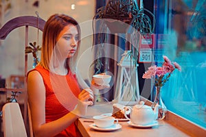 Sad woman eating dessert drinking tea in a coffee shop