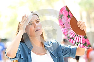 Sad woman fanning and sweating suffering a heat stroke photo