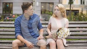 Sad woman feeling guilty, looking at jealous boyfriend, couple having fight