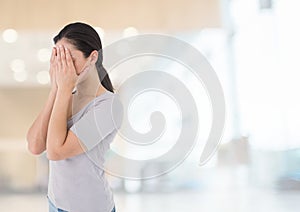 Sad woman grief hands over face against bright background