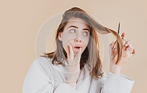 Sad woman having her hair cut with scissors. Beautiful woman in panic because of hair loss. Woman with hair loss problem