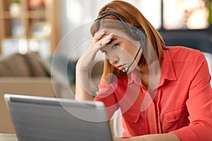 Sad woman with headset and laptop working at home