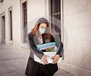 Sad woman holding box outside office feeling hopeless after being fired. Coronavirus job cuts crisis