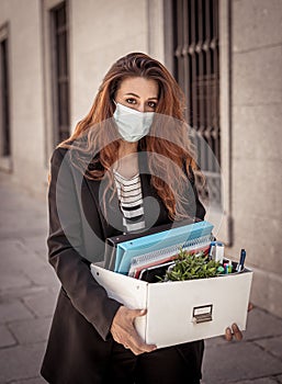 Sad woman holding box outside office feeling hopeless after being fired. Coronavirus job cuts crisis