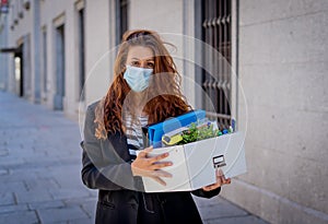 Sad woman holding box outside office feeling hopeless after being fired. Coronavirus job cuts crisis