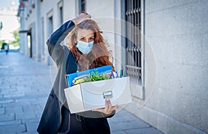 Sad woman holding box outside office feeling hopeless after being fired. Coronavirus job cuts crisis