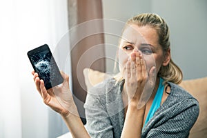 sad woman holding smart phone with broken screen