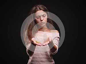 Sad woman holding tangled hair on the black background. Tuft of hair on a girl`s hand. Hair loss concept. Copy space.