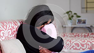 Sad woman hugging pillow on sofa