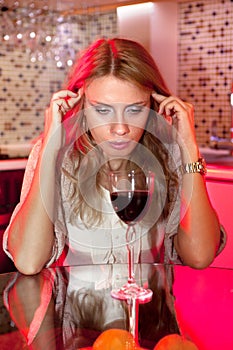 Sad woman in kitchen with glass of wine