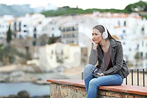 Sad woman listening to music in a coast town