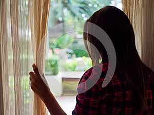 Sad Woman looking out a window, indoors.