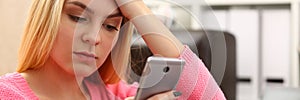 Sad woman looks at smartphone screen closeup