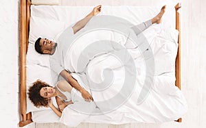 Sad woman lying in bed with sleeping man