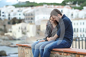 Sad woman and man comforting her on a ledge