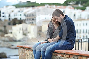 Sad woman and man comforting her on a ledge photo