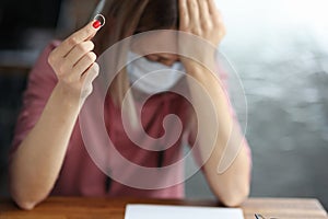 Sad woman in protective mask holding wedding ring in her hand