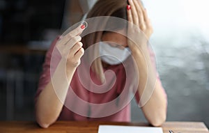 Sad woman in protective mask holding wedding ring in her hand