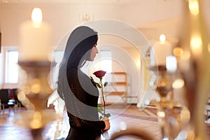 Sad woman with red rose at funeral in church